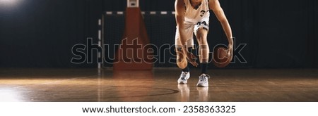 European Basketball Player Bouncing Ball on Wooden Court. Athlete Dribbling Basketball on Training Unit Royalty-Free Stock Photo #2358363325