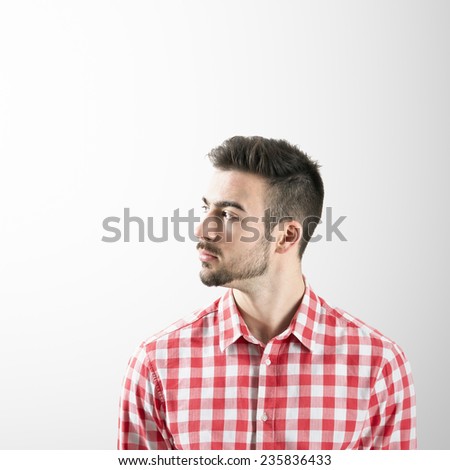 Profile of serious young bearded man looking away over gray background.