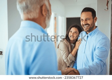 Friendly Real Estate Agent and young couple shaking hands standing in hallway, real estate agent handshaking clients at meeting, showing selling buying property for rent sale, discussing deal 