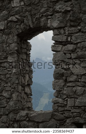 A mountain view through the stone window in old castles wall