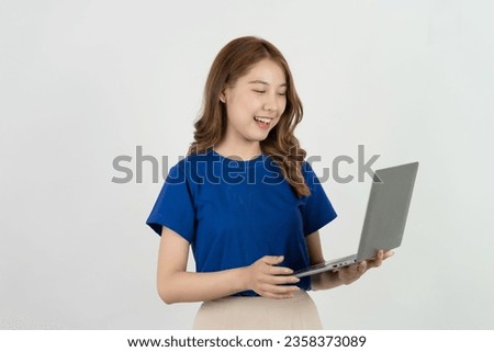 Happy asian woman in blue t-shirt holding laptop while celebrating online marketing success isolated on white background, online shopping concept
