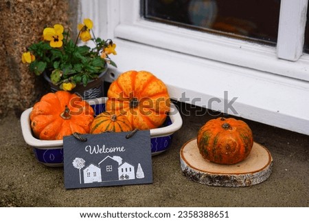 The fall pumpkins and yellow flowers with "Welcome" chalkboard sign in the window of a medieval house in Dinan, Brittany, France.