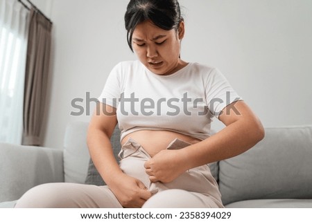 Fat chubby woman trying to wear tight pants, overweight, weight gain, Healthy and medical concept.
