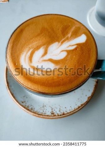 A close-up shot of a coffee cup filled with foamy cappuccino and  a floral pattern. This picture captures the rich aroma and flavor of freshly brewed coffee.