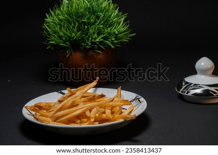 Kerala snack food spiced and salted tapioca stick or cassava chips, fried cassava chips , spicy masala tapioca chips or sticks in a black background top view side view, text space