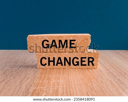 Brick blocks with words Game changer. Beautiful wooden table, dark blue background. Game changer business or political change concept and disruptive innovation.