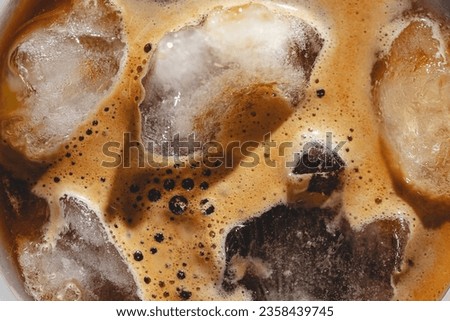 Texture Iced espresso coffee to wineglass with ice, top view, hard light. Royalty-Free Stock Photo #2358439745