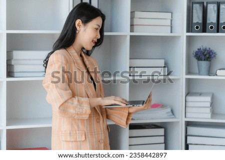 Confident young Asian business woman sitting with arms crossed smiling looking at camera in the office