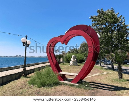 Photo zone on the embankment in the form of two red hearts with a bench. Special resting place for tourists. Beautiful place.