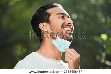 Smile, mask and remove with a man breathing fresh air in nature, feeling happy at the end of restrictions. Covid, freedom and post lockdown with a young person in the forest, woods or wilderness Royalty-Free Stock Photo #2358456457