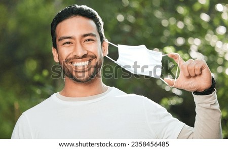 Portrait, mask and remove with a man breathing fresh air in nature, feeling happy at the end of restrictions. Covid, freedom and smile for post lockdown with a young person in the forest or woods Royalty-Free Stock Photo #2358456485