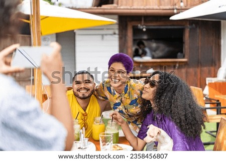 unrecognizable man taking a picture of a group of friends from the lgbt community and their pet outside a restaurant drinking natural juices. High quality photo