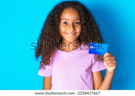 Photo of happy cheerful smiling positive Beautiful kid girl standing over blue background recommend credit card