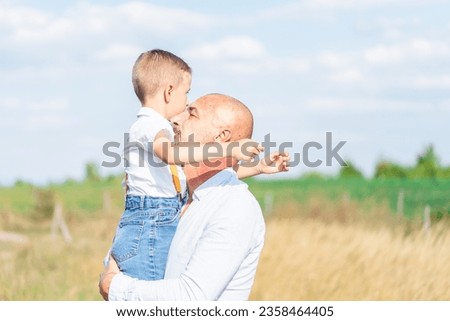 middle-aged man and his little son are playing in the field