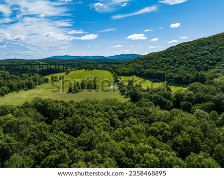 A high angle, aerial view over the hills and valleys of Salisbury Mills, NY on a beautiful day with blue skies and white clouds. Taken with a drone camera. Royalty-Free Stock Photo #2358468895