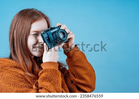 a woman with a camera near her face, a black camera and a woman on a blue background. photographer concept
