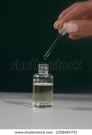 a glass perfume bottle in the hands of a woman on a green background