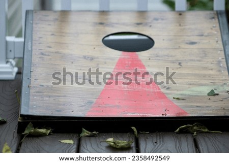 A cornhole game sitting on a deck in the Fall.