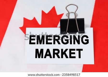 Economy and finance concept. On the flag of Canada lies a business card with the inscription - emerging market