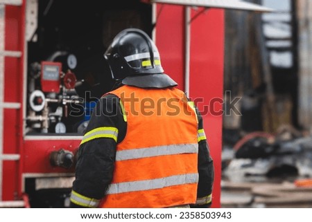 Group of fire men in protective uniform during fire fighting operation in the city streets, firefighters brigade with the fire engine truck vehicle in the background, emergency and rescue service