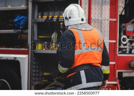 Group of fire men in protective uniform during fire fighting operation in the city streets, firefighters brigade with the fire engine truck vehicle in the background, emergency and rescue service Royalty-Free Stock Photo #2358503977