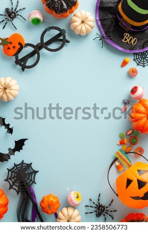Enthralling idea for children's Halloween night. Aerial vertical photo displaying candies, young ones' costume elements and eerie ornaments on isolated blue setting, providing space for adverts or tex