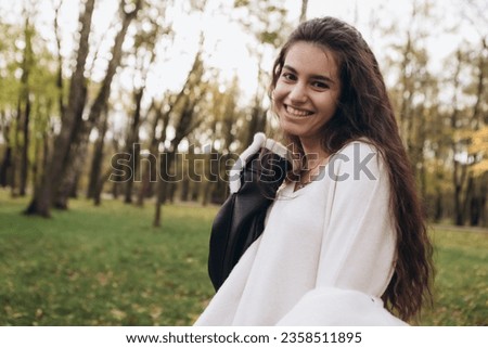 Attractive pretty woman walking outdoor, portrait of young lady in warm sunny autumn park season, fall, yellow orange red leaves, dressed leather wool fur jacket smiling having fun 