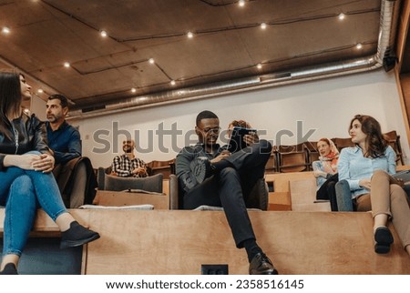 Male business person working on tablet during brainstorming with his coworkers at small amphitheater in big business center