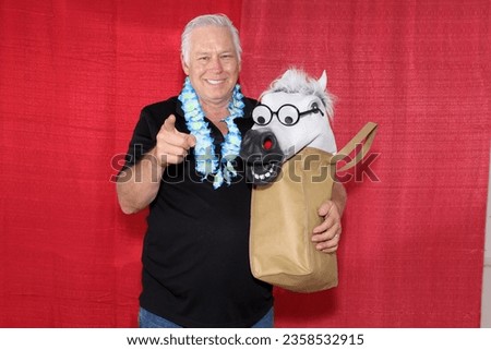 Photo Booth. A man holds a Reusable Cloth Shopping Bag with a Horse Head looking out while in a Photo Booth getting his Pictures Taken. Everyone loves a Photo Booth. Wedding Photo Booth. Birthday Pics