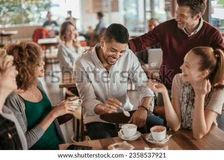 Young and diverse group of people talking while having coffee together in a cafe Royalty-Free Stock Photo #2358537921