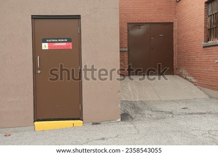 electrical room sw danger arc flash and shock hazard appropriate ppe required sign on brown metal full entrance door and others next to it