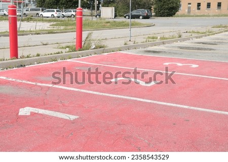 three red parking spots spaces with numbers 1 2 3 in each of them side by side in white for pickup with cars vehicles on road street in background