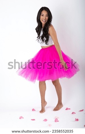 Asian woman in pink tutu skirt against white background