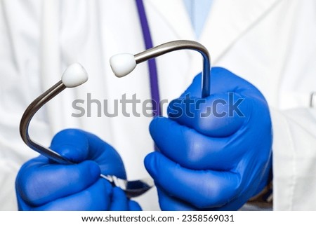 Extreme close-up of an unrecognizable doctor's hands wearing blue gloves holding earpieces of a stethoscope.