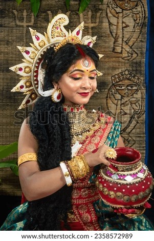 Portrait of beautiful Indian girl of Durga idol Agomoni Concept Indoor Photo. wearing traditional Indian saree, gold jewellery,Maa Durga agomoni shoot concept .Indian culture durga puja.