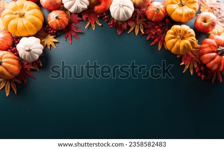Thanksgiving and Autumn decoration concept made from autumn leaves and pumpkin on dark background. Flat lay, top view with copy space.