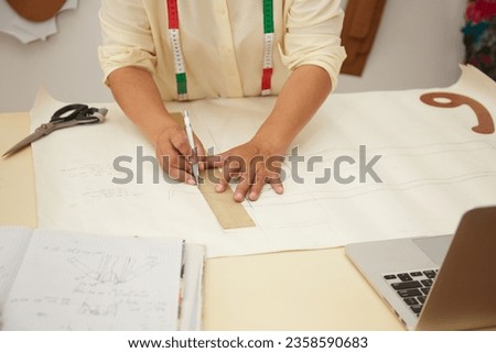 Photo of Asian Fashion Designer drawing and making paper sketches 