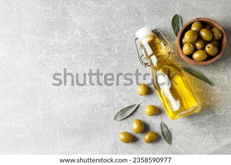 Bottle of olive oil and olives on gray background, space for text