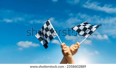 Two checkered race flags in hand Royalty-Free Stock Photo #2358602889
