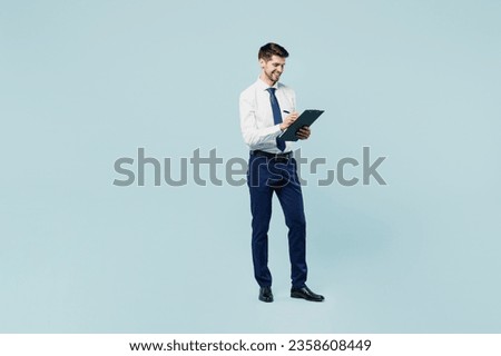 Full body young employee IT business man corporate lawyer wear classic formal shirt tie work in office hold clipboard with paper account documents isolated on plain pastel light blue background studio
