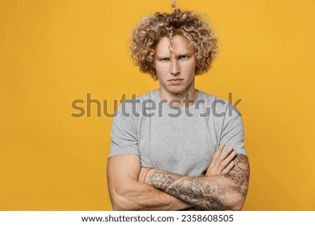 Young sad displeased dissatisfied depressed caucasian man 20s he wear grey t-shirt hold hands crossed folded look camera isolated on plain yellow background studio portrait. People lifestyle concept Royalty-Free Stock Photo #2358608505