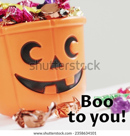 Composite of boo to you text and halloween pumpkin bucket and sweets on white background. Halloween, tradition and celebration concept digitally generated image.