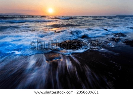 A seascape photographed with a long exposure technique at sunset. 

