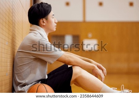 Japanese male university student practicing basketball in the gymnasium