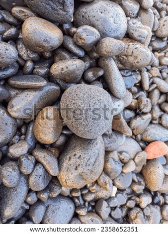 piles of spherical volcanic rocks on the beach, Wet Gray Pebbles Closeup, Textured Background, low light