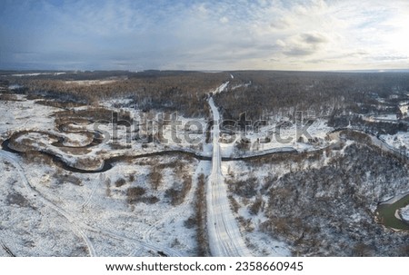 Aerial photo panorama of Koen river and road bridge under ice and snow. Beautiful winter landscape. Novosibirsk, Siberia, Russia
