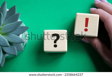 Question mark and exclamation mark symbol. Question mark and exclamation mark on wooden cubes. Businessman hand. Beautiful green background with succulent plant. Business concept. Copy space.