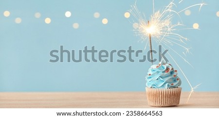 Tasty cupcake with sparkler on light blue background with space for text