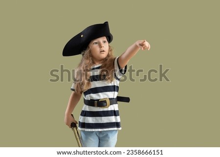 Cute little girl dressed as pirate with spyglass pointing at something on green background Royalty-Free Stock Photo #2358666151