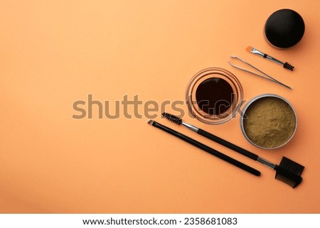 Flat lay composition with eyebrow henna and professional tools on orange background, space for text
